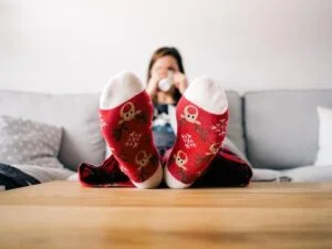 A lady drinking tea at home with her feet on the coffee table