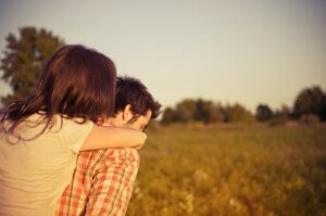 A man carrying a woman on his back through a field