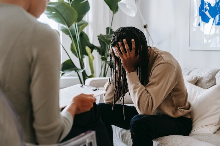 A man in a drug or alcohol therapy session looking stressed