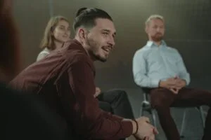 A man sitting at an AA meeting smiling at drug and alcohol rehab in Bedfordshire