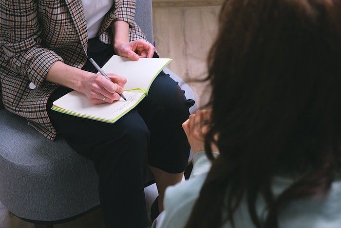 A person holding pen and paper during a meeting with a therapist for drug and alcohol addiction at rehab in Lancashire