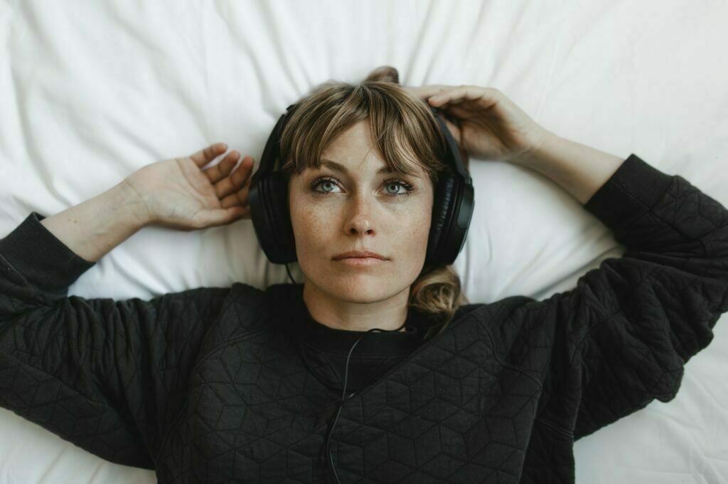 woman lies in bed with headphones