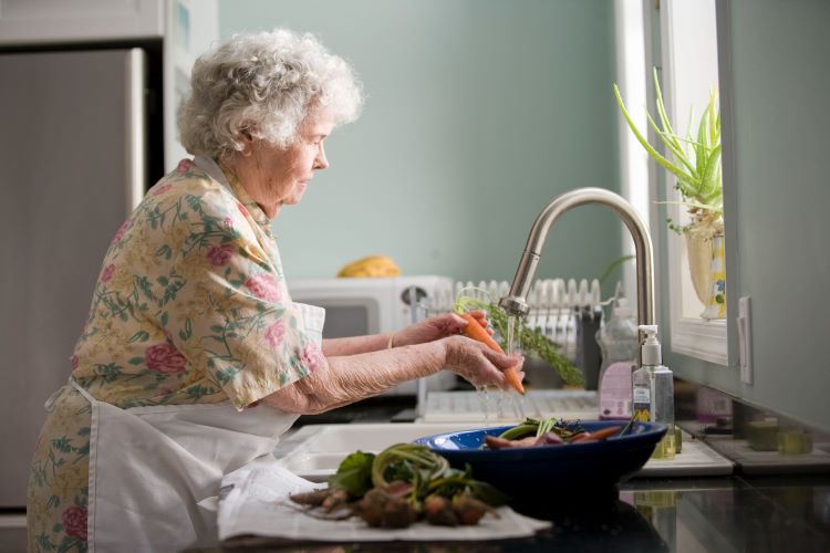 An elderly woman washing up