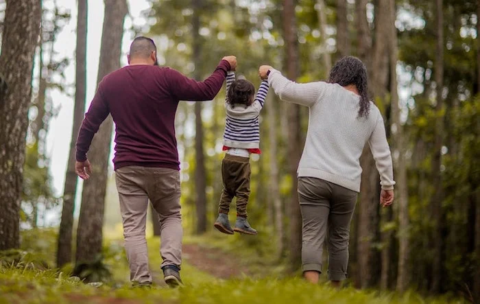 Mother and father swinging their child between them in Reading