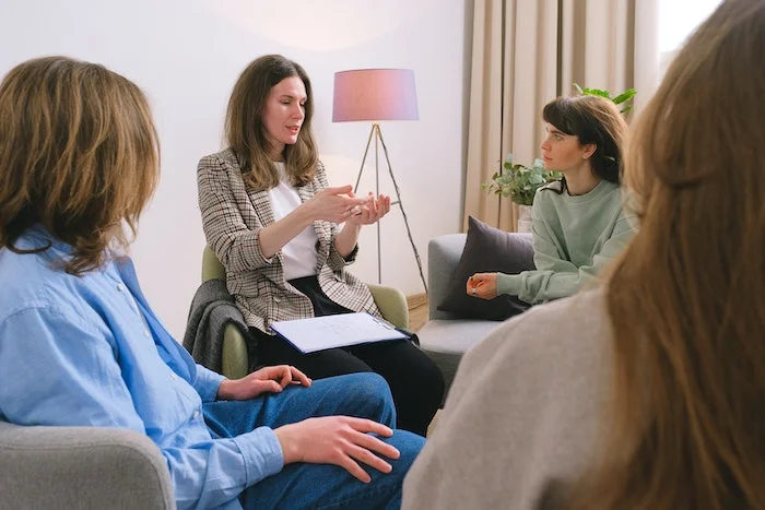 A group therapy session with a woman talking to a family at luxury rehab for addiction