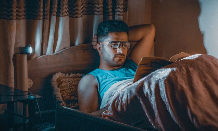 Man lying in bed reading a book at a drug and alcohol rehab clinic in Hertfordshire