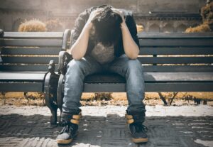 Man sitting on bench holding his head in his hands during detox at a rehab in Bristol