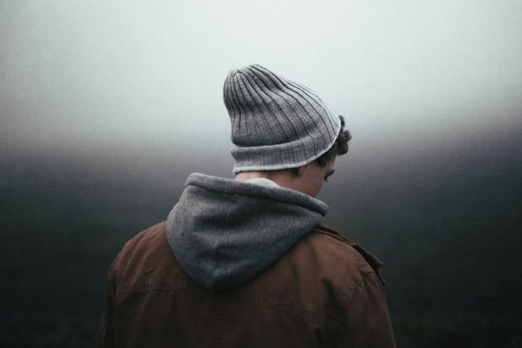 A man turning away. The sky behind him is grey