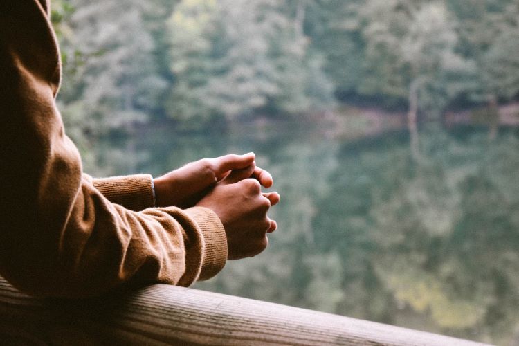 person leaning on ledge and looking out at lake