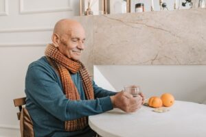 Old man sitting at a table holding a drink