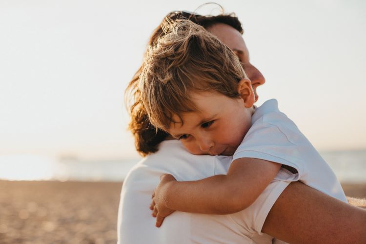 A mother carrying her son on the beach