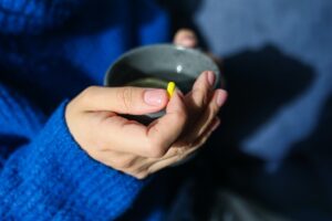 Person holding medication and tea at rehab