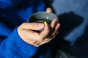 A person holding medication and tea at drug and alcohol rehab