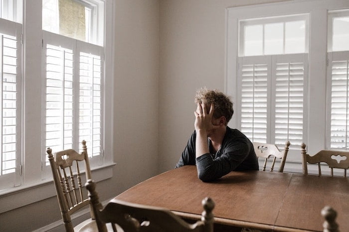 Person leaning on a table holding his head at a drug and alcohol rehab centre in Hampshire