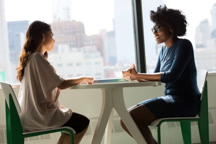 Two women talking at a table during individual therapy for addiction rehabilitation
