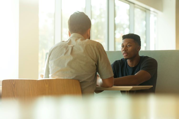 Two men chatting across a table at drug and alcohol rehab in Buckinghamshire