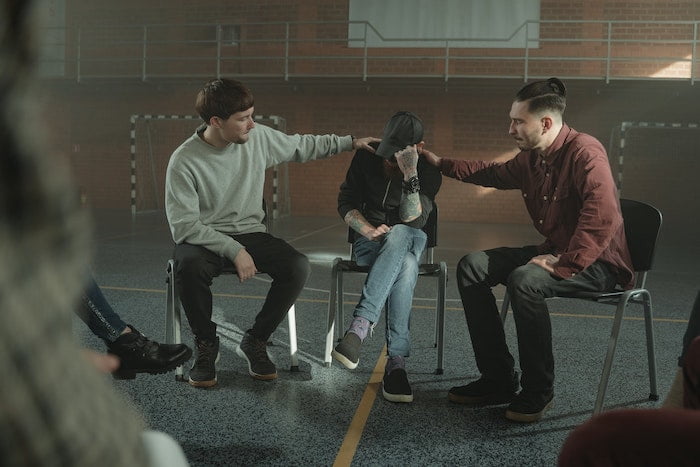 Two men comforting another man in a group therapy session at drug and alcohol rehab in Berkshire