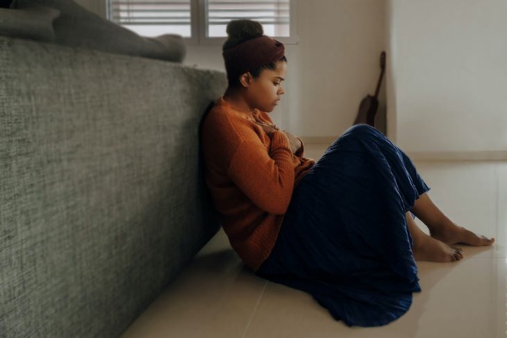 A woman sat behind a sofa looking anxious