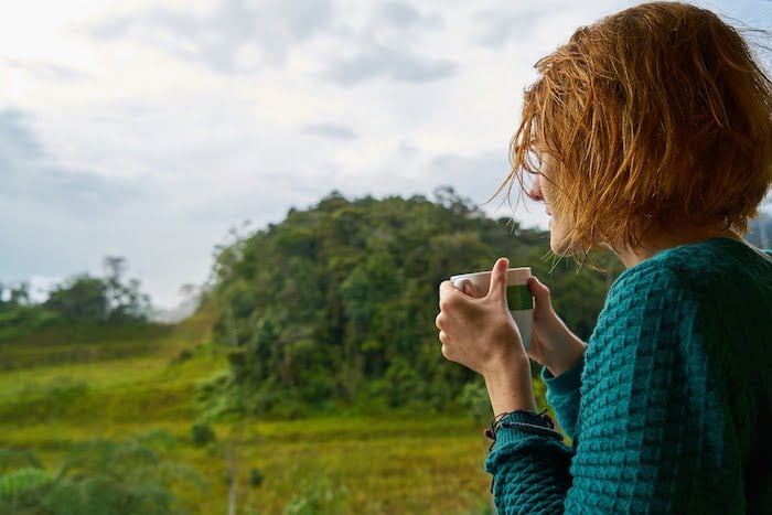 Woman drinking a cup of tea and looking at the countryside at a drug and alcohol rehab in Essex