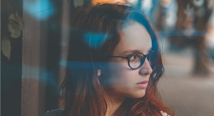 A freckled woman in glasses, looking away