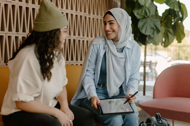 Two women talking and looking at a tablet