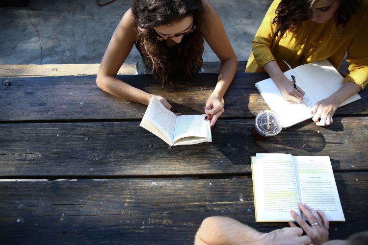 Three people writing at a table