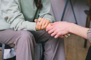 Two people sitting, holding hands