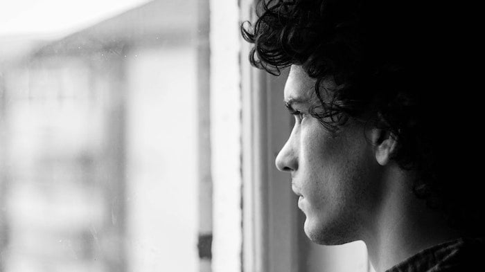 Black and white photo of a man staring out of a window at a drug and alcohol rehab centre in Hull