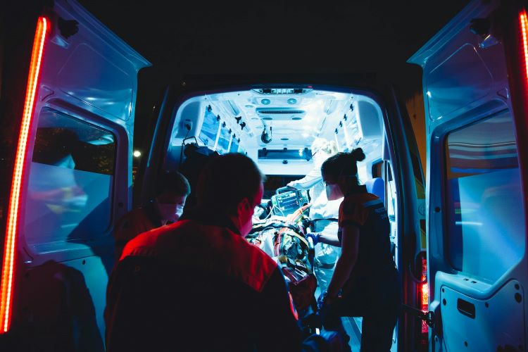 The back of an ambulance illuminates paramedics