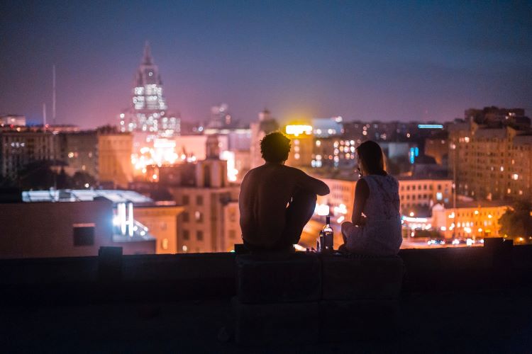 Two people drinking looking at a city skyline