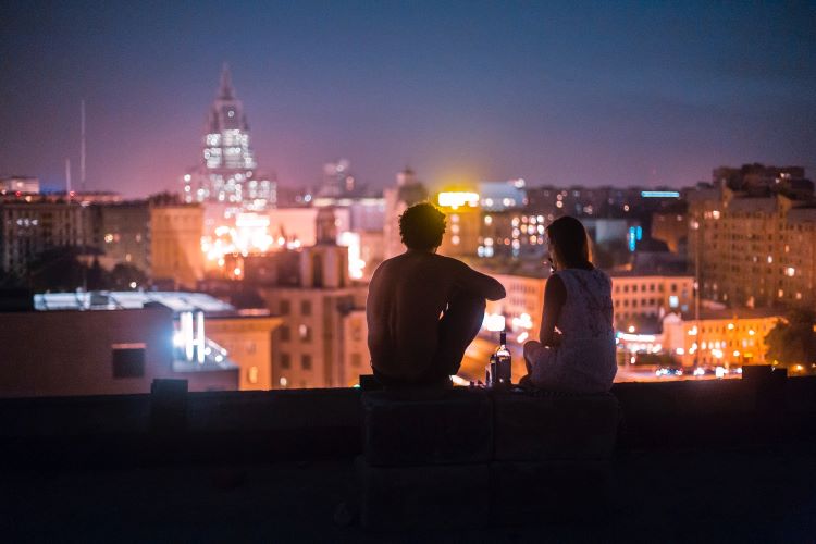 Two people drinking looking at a city skyline
