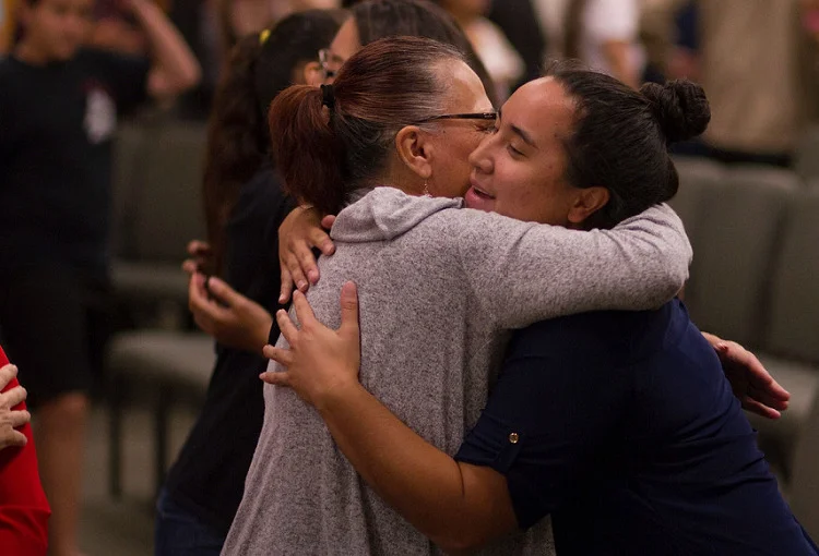 Two women hugging at a public meeting