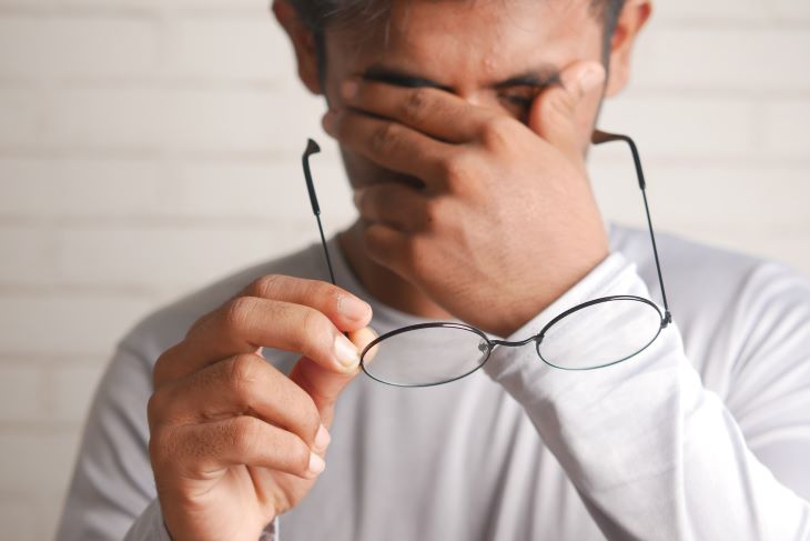 Man taking off his glasses and rubbing his face