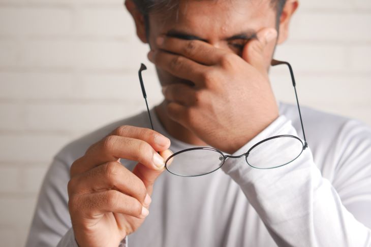 Man taking off his glasses and rubbing his face suffering from alcohol withdrawal symptoms