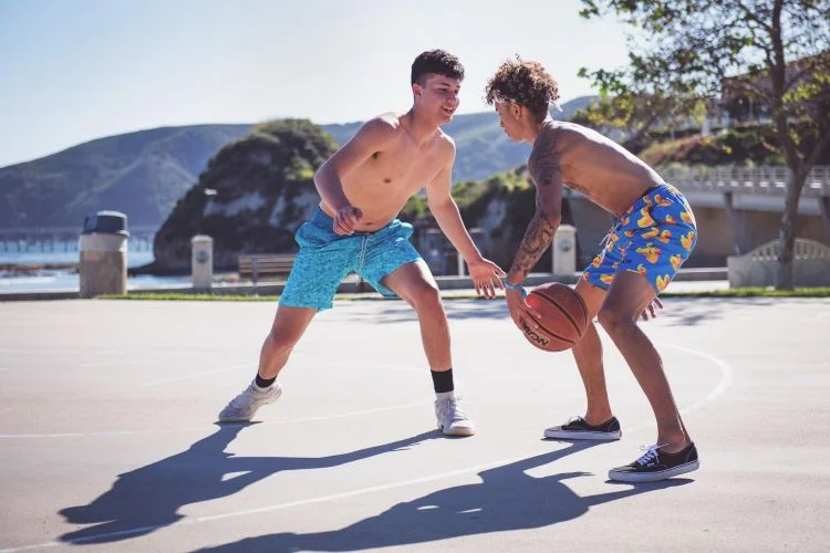 Two young men playing basketball in the sun