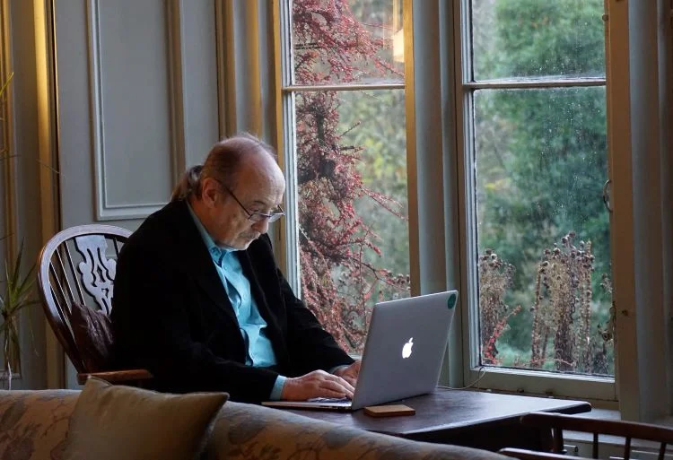 Elderly man typing on a laptop