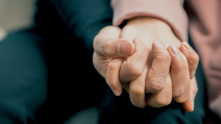 Older person and younger person holding hands at a drug and alcohol rehab in Guildford