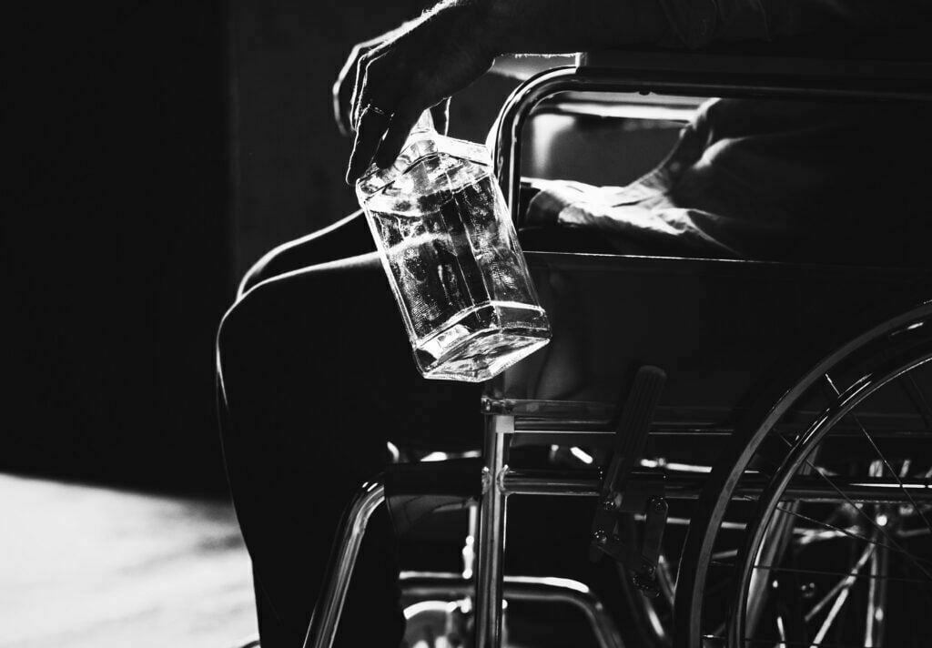 man sat in wheelchair with bottle of alcohol