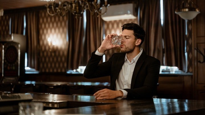 A man drinking from a small glass in a pub in Cardiff