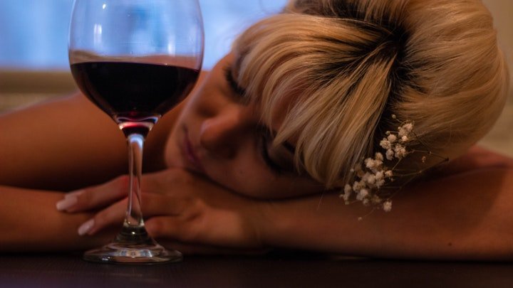 A woman passed out next to a wine glass