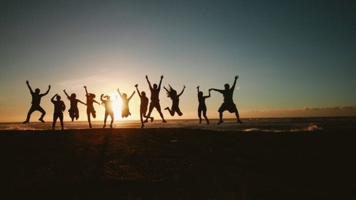 People jumping in a line silhouetted against the sun in Cambridge