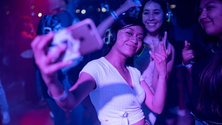 Two women taking a photo in dim club lighting