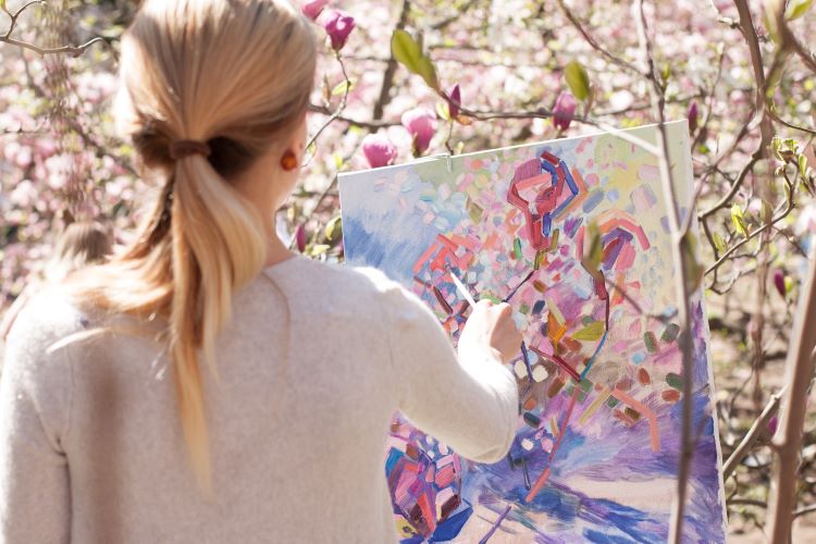 Woman painting with pink flowers behind