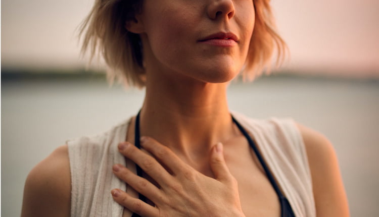 A woman with her hand on her chest, breathing