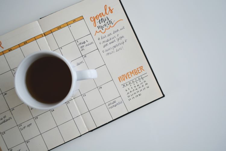 A paper calendar with added goals set out during motivational interviewing for addiction. A black coffee on top