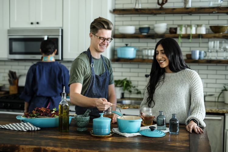 A chef teaching a woman to cook in a rehab kitchen with blue pans