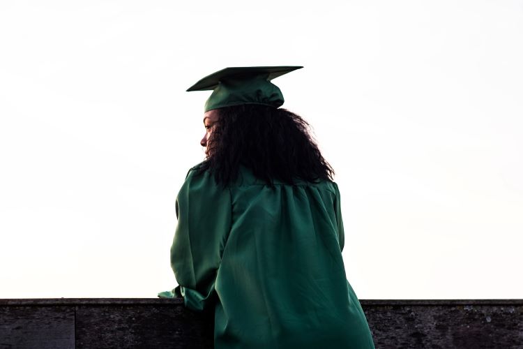 A woman in graduation gowns looking pensive