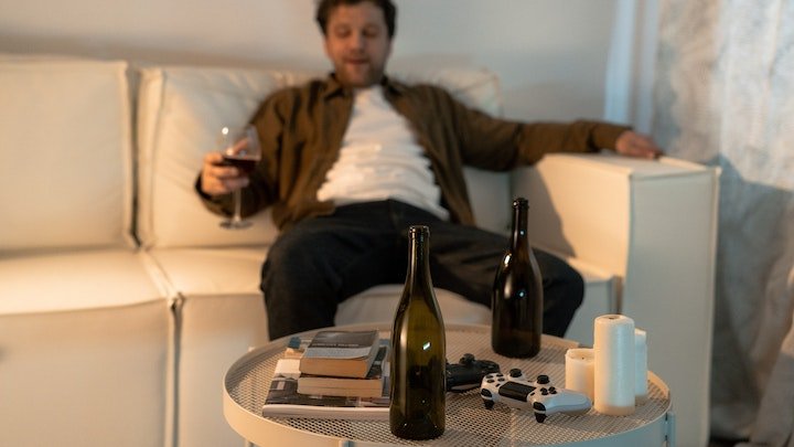man sat on sofa drinking wine