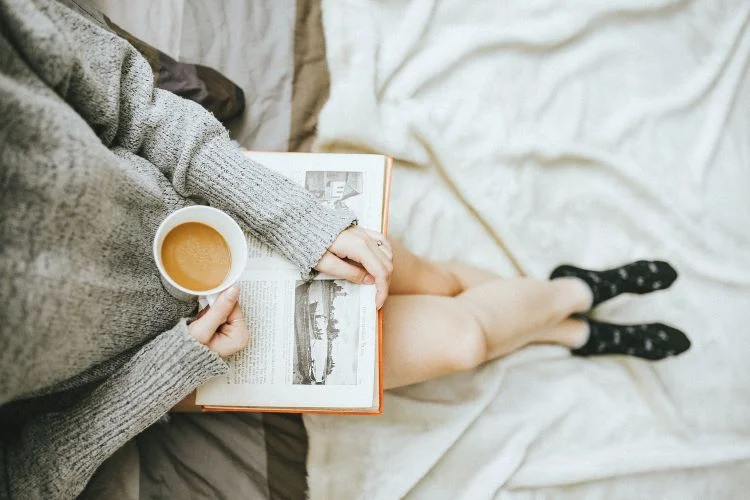 A woman reading in bed with a coffee