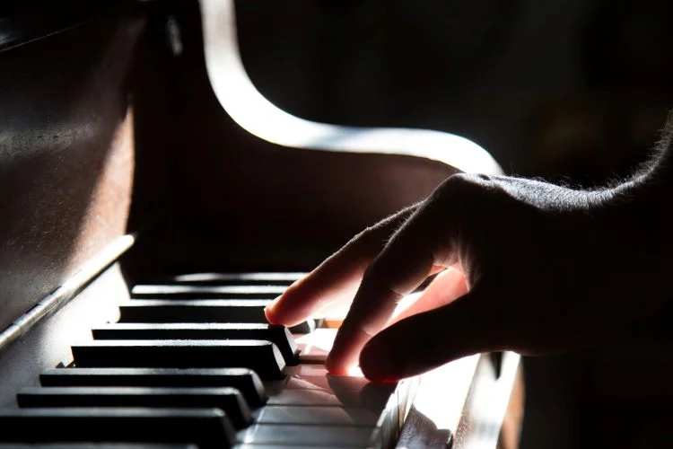A hand playing a piano in music therapy